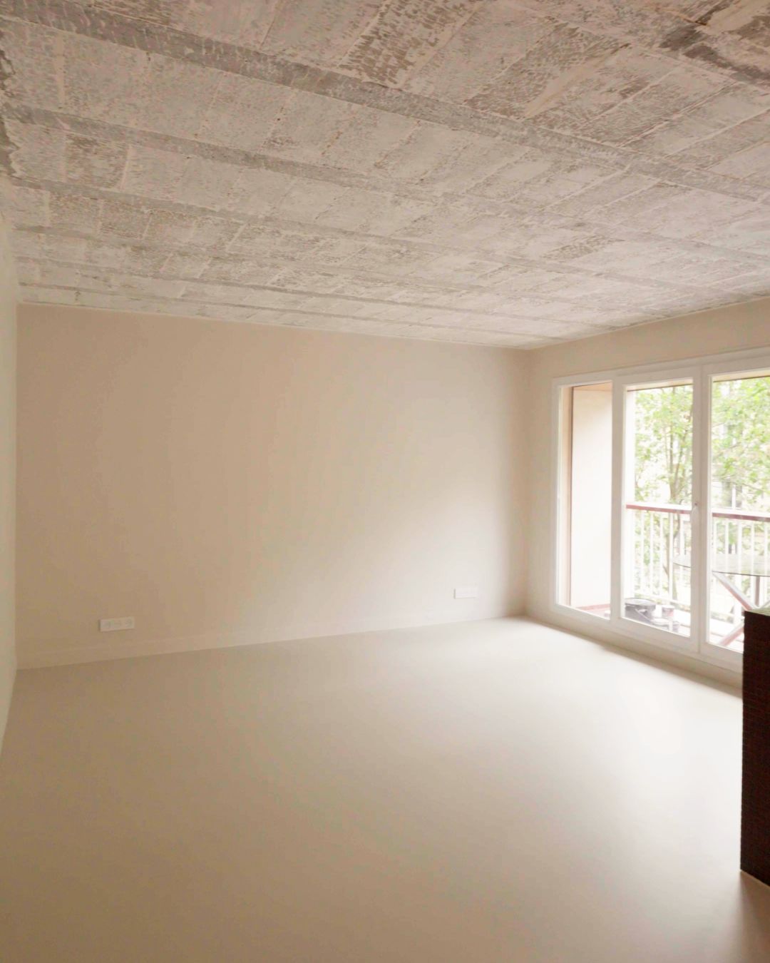 Salon rénové avec plafond béton apparent